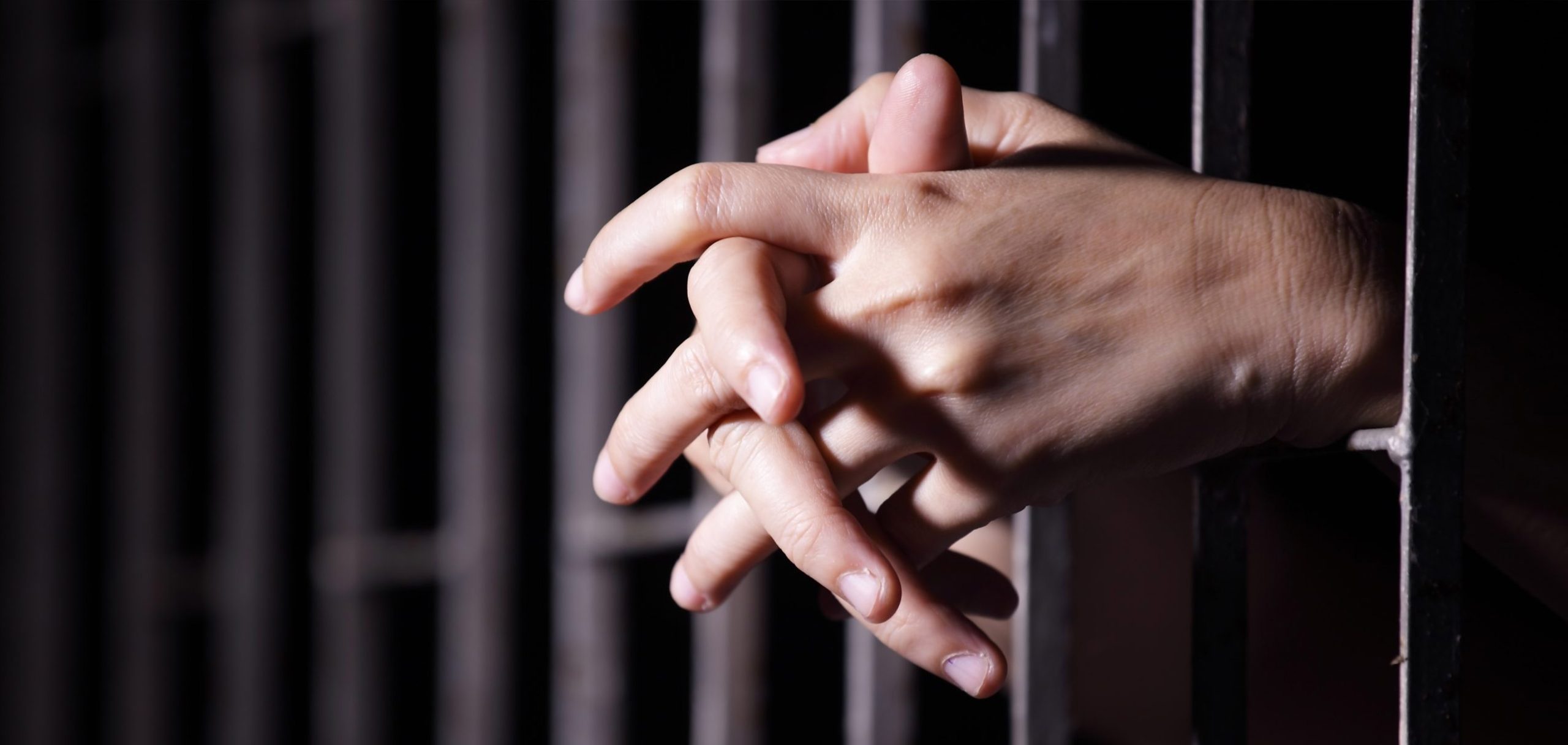 Egy rab kezei a börtön rácsain.