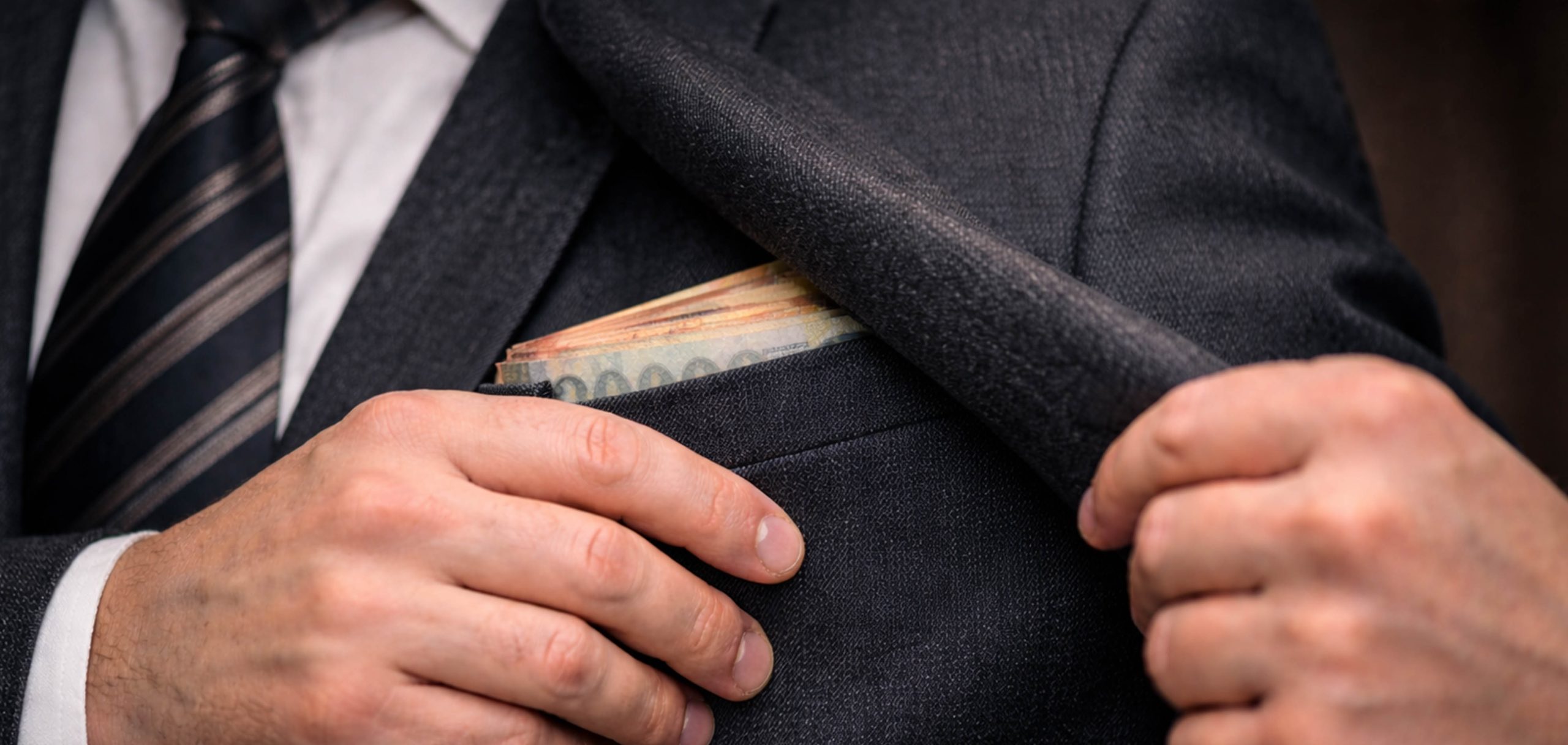 Egy férfi pénzt rejt a zsebébe.